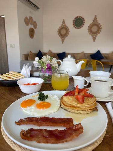 a breakfast plate with eggs bacon and pancakes on a table at Hotel Boutique Casa chunuu Santa Marta in Santa Marta