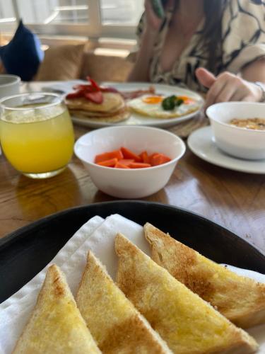 a table with a plate of food with toast and orange juice at Hotel Boutique Casa chunuu Santa Marta in Santa Marta