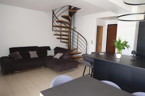 - un salon avec un canapé noir et un escalier en colimaçon dans l'établissement Spacious house for 8 with swimming pool, à Antibes