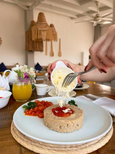 a person pouring food on a white plate with a plate of food at Hotel Boutique Casa chunuu Santa Marta in Santa Marta