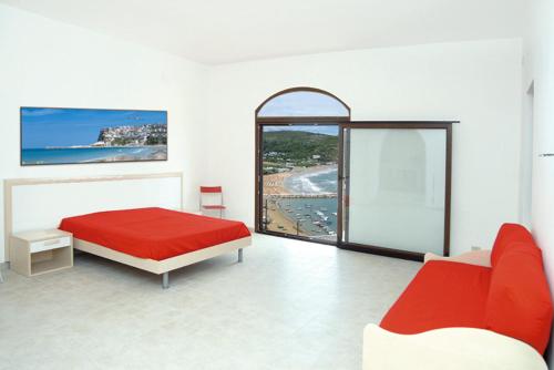 a bedroom with a red bed and a large window at Appartamenti Castello in Peschici