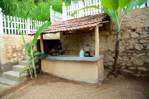 an outdoor kitchen in a stone building with a white fence at Ella Village House in Ella