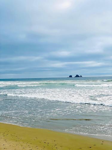 a beach with the ocean and a rock in the distance at Casa Brisse - Playa y Naturaleza in Salango