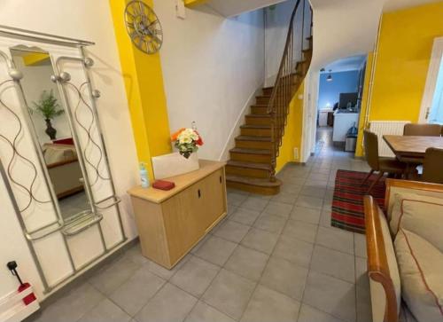 un couloir avec un escalier aux murs jaunes et un miroir dans l'établissement Maison de charme 86m2 à Saint-Denis Pleyel, 4 chambres, terrasse, calme, proche Paris et Stade de France, à Saint-Denis