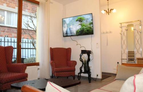 - un salon avec 2 chaises et une télévision murale dans l'établissement Maison de charme 86m2 à Saint-Denis Pleyel, 4 chambres, terrasse, calme, proche Paris et Stade de France, à Saint-Denis