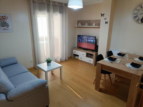 a living room with a blue couch and a television at Piso PLAYA CANGAS CENTRO in Cangas de Morrazo