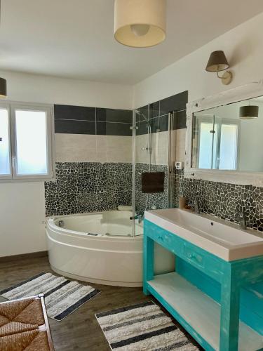 une salle de bain avec une baignoire blanche et une table bleue dans l'établissement Chambre cosy avec petit déjeuner chez Olivier et Manuel à Clavette, proche La Rochelle, à Clavette