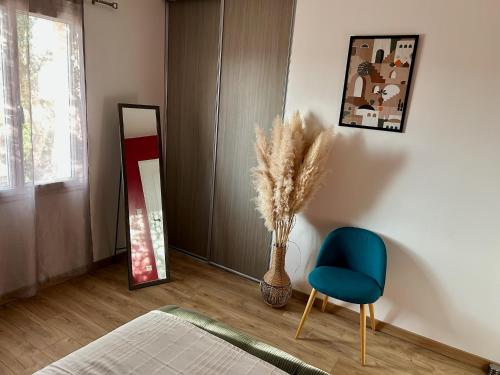 une pièce avec une chaise bleue et un vase avec des plumes dans l'établissement Chambre cosy avec petit déjeuner chez Olivier et Manuel à Clavette, proche La Rochelle, à Clavette