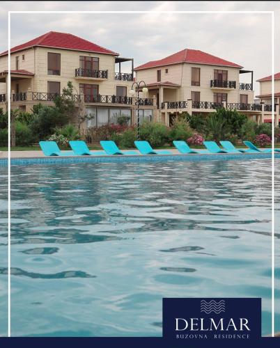 a pool with blue lounge chairs in front of buildings at Delmar resıdence in Mekhrably