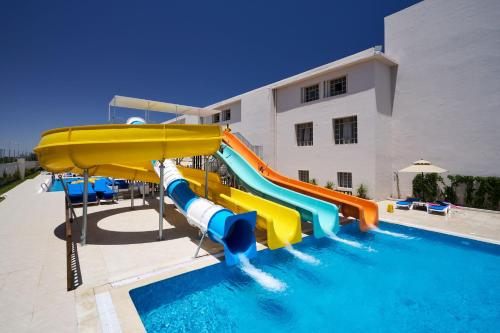 a water slide in a pool next to a building at TUI SUNEO Palm Beach Skanes - All Inclusive in Monastir