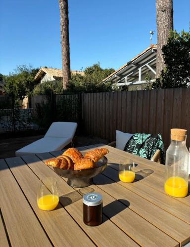- une table avec un bol de pain et deux verres de jus d'orange dans l'établissement Maison neuve Lacanau à 300m de la plage sud et à proximité des golfs, à Lacanau