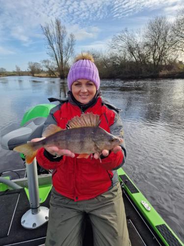 a woman holding a fish in her hands on a boat at Rose Glamping pod in Derrylin