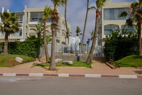 a building with palm trees in front of a street at Magnifique studio cosy et lumineux avec vue sur mer in Tamaris