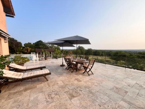 un patio avec une table, des chaises et un parasol dans l'établissement Vue exceptionnel-Piscine chauffée-salle de sport, à Saint-Jean-de Laurs
