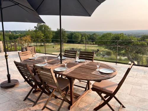 - une table en bois avec des chaises et un parasol sur la terrasse dans l'établissement Vue exceptionnel-Piscine chauffée-salle de sport, à Saint-Jean-de Laurs