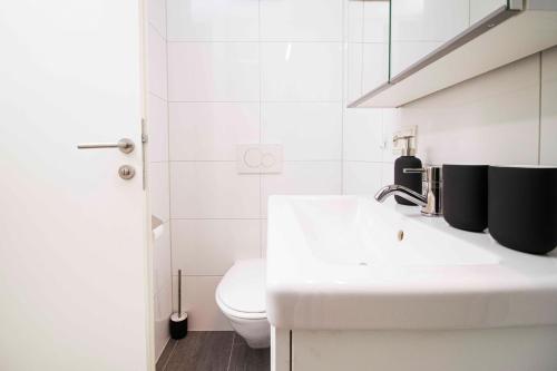 a white bathroom with a sink and a toilet at Apartmenthaus ROSE in Prutz