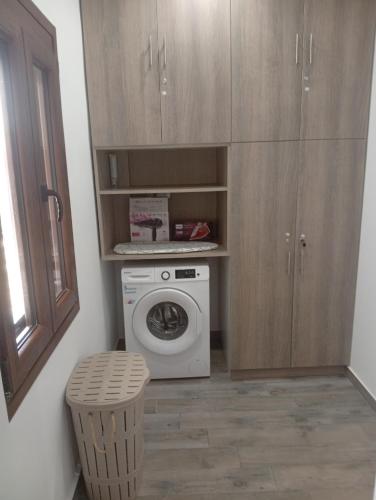 a small kitchen with a washing machine and a stool at Nea Vrasna Sun House in Nea Vrasna