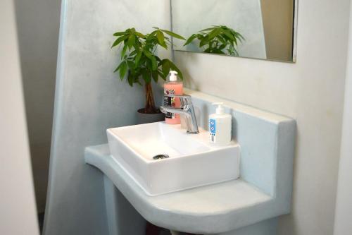 lavabo blanco en un baño con planta en Helen Apartment, en Ermoupoli