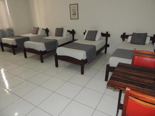 a room with four beds and a bench at Hotel Nobrega - São Paulo - Aeroporto Congonhas in Sao Paulo