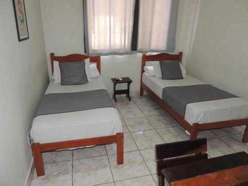 two beds in a small room with a table at Hotel Nobrega - São Paulo - Aeroporto Congonhas in Sao Paulo