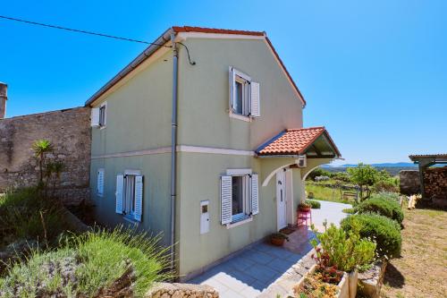 Una pequeña casa con persianas azules. en Green House, en Nerezine
