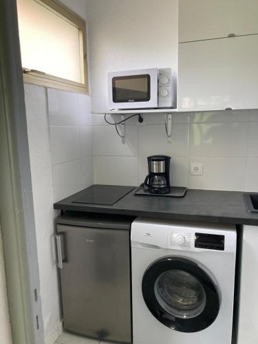 une cuisine avec un lave-linge et un micro-ondes dans l'établissement A 5 minutes du centre de Juan les pins et de la mer ! Appartement dans résidence avec piscine et terrain de tennis, à Antibes