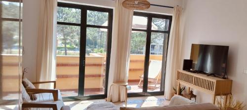 a living room with a tv and large windows at Boho Beach Apartment in Praia de Mira
