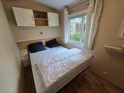 un petit lit dans une chambre avec une fenêtre dans l'établissement Mobil Home 829-4 accès piscines inclus en Juillet-Aout dès 4 nuitées, à Gastes