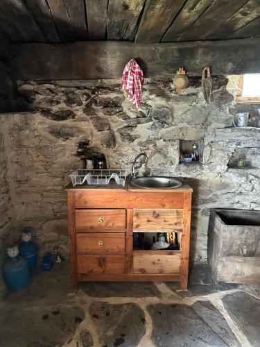 une cuisine avec un évier et un mur en pierre dans l'établissement La bayta de mon père, à Réotier