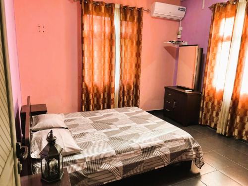 a bedroom with a bed and orange and pink walls at Vacation House with Private Pool in Baie du Tombeau