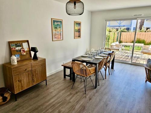 une salle à manger avec une table et des chaises noires dans l'établissement Maison neuve Lacanau à 300m de la plage sud et à proximité des golfs, à Lacanau
