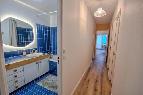 La salle de bains est pourvue de carrelage bleu, d'un lavabo et d'un miroir. dans l'établissement Suite T6 Rennes - Idéal Entreprises & Familles, à Rennes