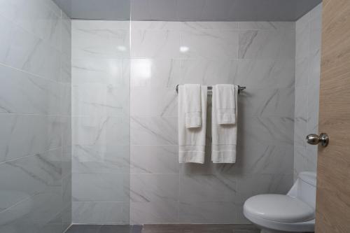 a bathroom with a toilet and white towels at Plaza colonial suites by Yellowkey in Santo Domingo
