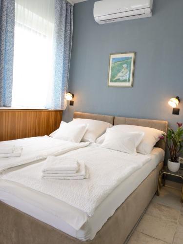 a bedroom with a large white bed with a window at Angéla Vendégház in Zalakaros