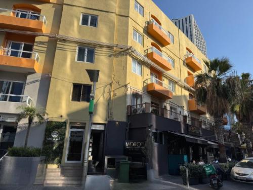 a yellow building with palm trees in front of it at Miami Apartments in St. Julianʼs