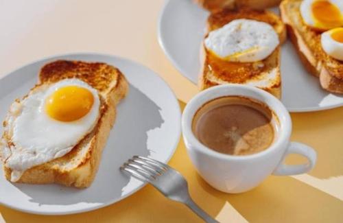 a plate of eggs and toast with a cup of coffee at Dubai Guest House Karachi in Karachi