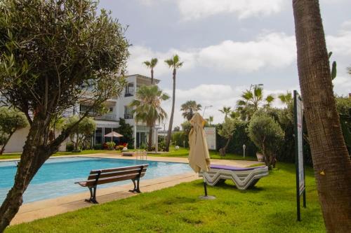 a pool with a bench and an umbrella next to a house at Magnifique studio cosy et lumineux avec vue sur mer in Tamaris