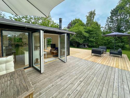 an outdoor deck with an umbrella and chairs at Liseleje sommerhus på naturgrund in Melby