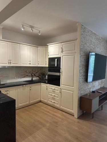 Eine Küche mit weißen Schränken und einem Fernseher an der Wand. in der Unterkunft Prime Apartment in Tirana