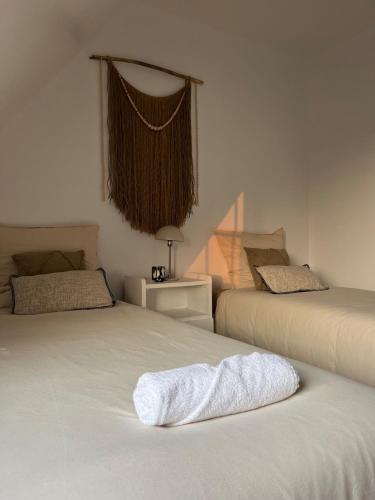 - une chambre avec 2 lits et une serviette blanche sur le lit dans l'établissement Échappée Belle du Mont-Saint-Michel, à Saint-Georges-de-Gréhaigne