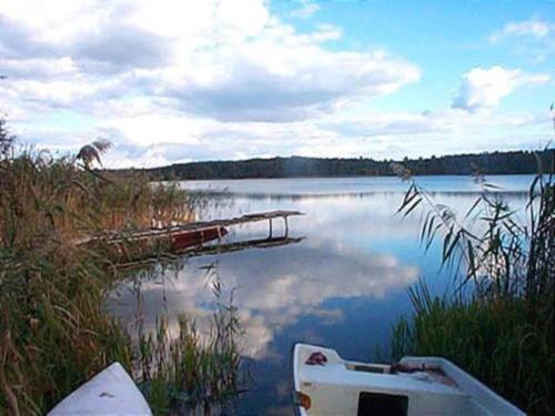 a boat sitting on the shore of a lake at Holiday Home in Skrzynia near Lake & Forest in Osiek