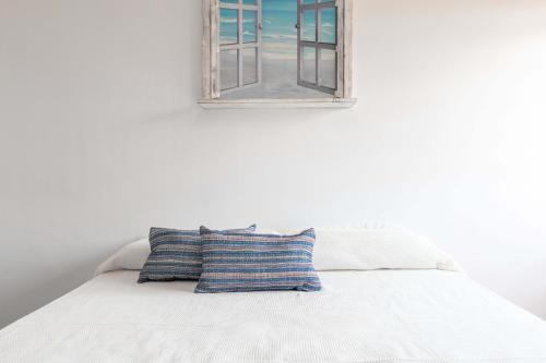 a pillow sitting on a bed with a window at Casa Saona En Riumar ( a 100m de la playa ) in Riumar