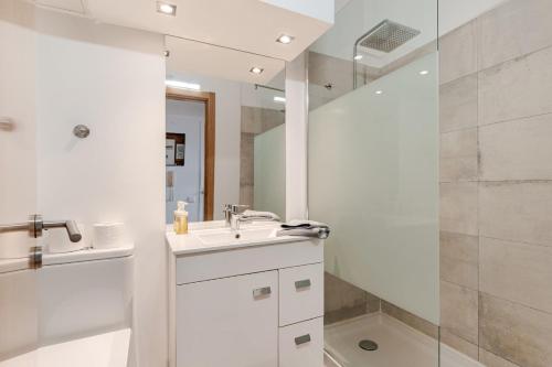 a white bathroom with a sink and a shower at Gallarija Caparica in Costa da Caparica