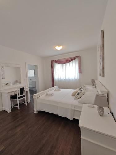 a bedroom with a large white bed and a desk at Vila Kathy - kuća za odmor in Seget Vranjica