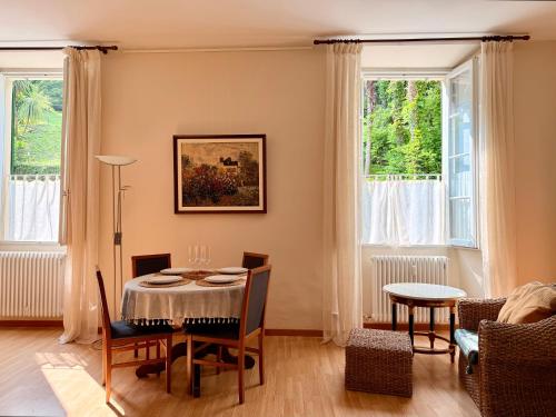 a dining room with a table and chairs and two windows at BELLE ILE PARK in Griante Cadenabbia