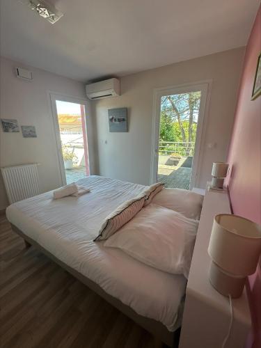 un grand lit dans une chambre avec une grande fenêtre dans l'établissement Toit terrasse à Andernos les Bains, à Andernos-les-Bains
