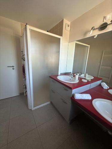La salle de bains est pourvue de 2 lavabos et d'un comptoir rouge. dans l'établissement Toit terrasse à Andernos les Bains, à Andernos-les-Bains