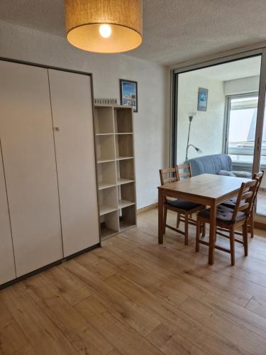 uma sala de jantar com mesa e cadeiras e uma janela em Studio 250m mer et Seaquarium avec place parking em Le Grau-du-Roi