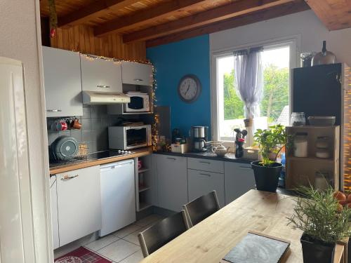 une cuisine avec des armoires blanches et une table en bois dans l'établissement Cosy et chaleureux, à Lau-Balagnas