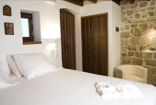 un letto bianco in una stanza con un muro di pietra di Domus Studios a Città di Rodi